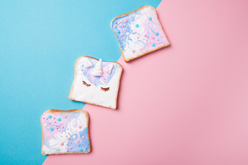 Unicorn and mermaid toasts with stars, food for kids idea, top view on a blue and pink background