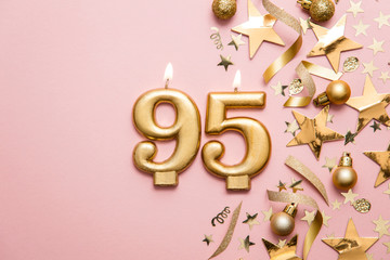 Number 95 gold celebration candle on star and glitter background