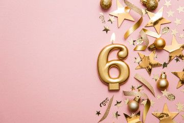 Number 6 gold celebration candle on star and glitter background