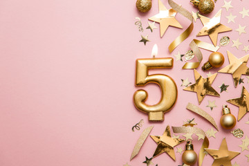 Number 5 gold celebration candle on star and glitter background