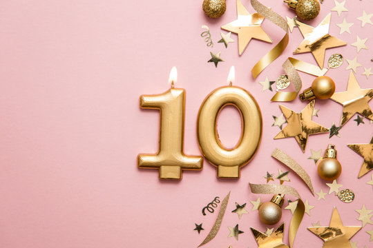 Number 10 gold celebration candle on star and glitter background - Powered by Adobe