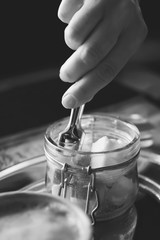 A woman takes sugar with special tweezers in a cafe. Close-up. Black and white vertical photo.