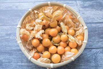 Cape gooseberry fruits in the basket (Physalis peruviana) on wooden background.Commonly called goldenberry, golden berry, Pichuberry.