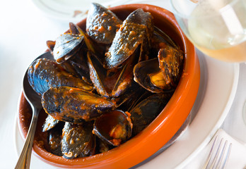 Fototapeta premium Delicious baked mussels on a bowl with spoon at table