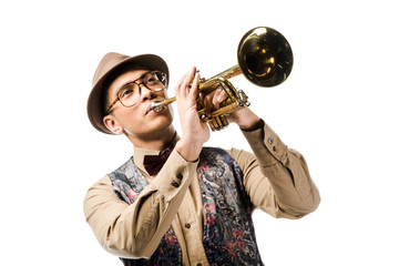 young mixed race man in stylish hat and eyeglasses playing on trumpet isolated on white