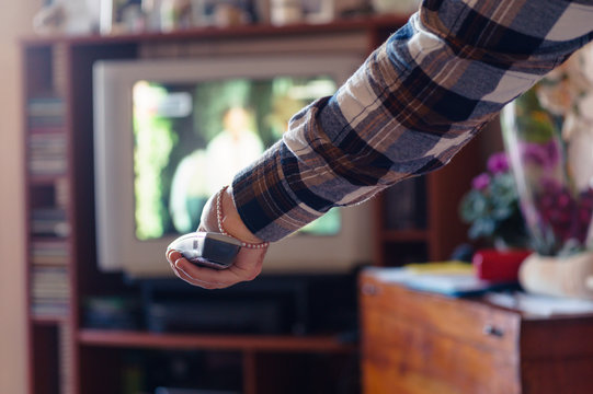 In a tiny living room a guy is zapping on his old television