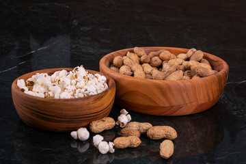 Peanuts with Popcorn in golden wood bowl on black marble table