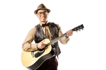 Obraz premium happy mixed race male musician in hat and eyeglasses playing on acoustic guitar isolated on white