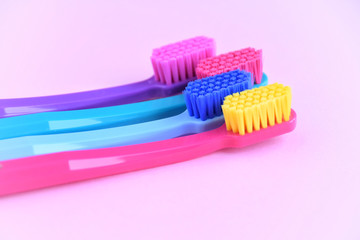 Four  multicolored toothbrushes with selective focus on pink background. Toothbrush for personal routine morning  hygiene on neutral backdrop. Dental plastic tool with empty space for image or text