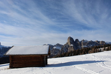Panorama con montagne delle alpi dolomitiche con cielo e nuvole ed una capanna alpina sulla neve