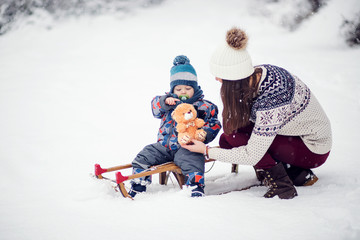 Mom gives a gift to her child,mother and son and sledge at winter day