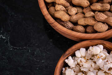 Peanuts with Popcorn in golden wood bowl on black marble table