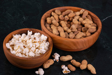 Peanuts with Popcorn in golden wood bowl on black marble table