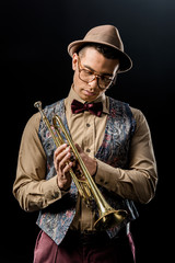 mixed race male musician posing with trumpet isolated on black