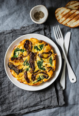 Porcini mushrooms, potatoes, spinach baked frittata - delicious breakfast, snack, tapas on a gray background, top view