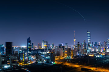 Fototapeta na wymiar Kuwait city skyline at night with aircraft climbing from Kuwait Airport at the background