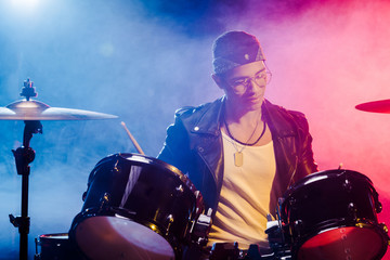 Fototapeta na wymiar young mixed race male musician playing drums during rock concert on stage