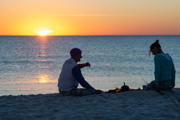Romantic couple relaxes on a beach, making coffee on fire