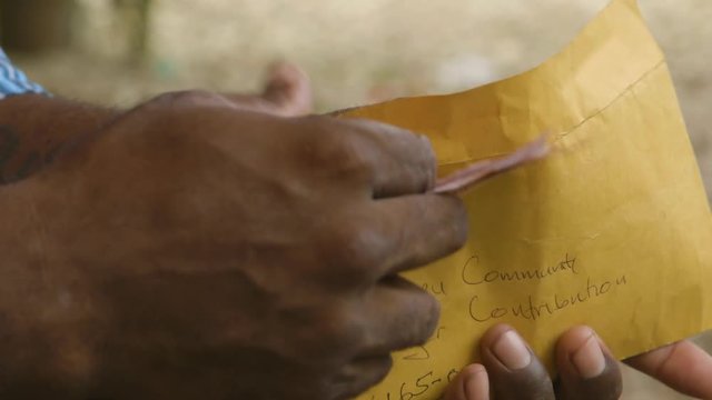 A closeup shot of mans hand putting some money in envelope 