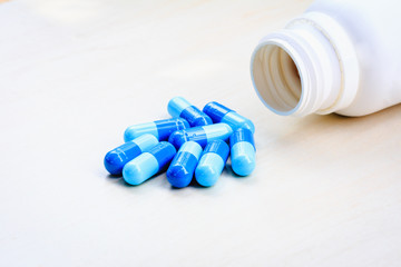 Blue pills (medicine) and an open white pot. Selective focus.