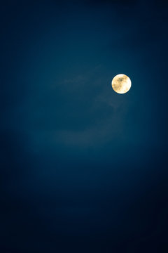 A scary yellow fool moon of a dark sky with clouds, mystical night background.