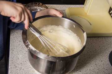 Iron bowl with dough in which the whisk mix the ingredients