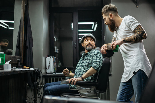 Bearded barber looking at his client while talking to him