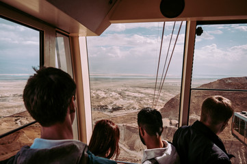 A group of people traveling the famous cable car lift the Massada Clifftop. Israel