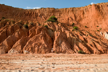 a woman sitting at the bottom of giant red dunes