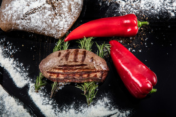 Top view of grilled filet mignon beef steaks on a black wooden surface