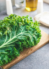 The kale bunch on a wooden cutting board in a kitchen. The concept of healthy and vegan food.