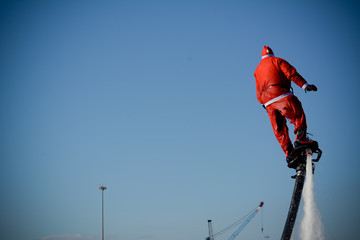 Horizontal View of Santa Claus on Flyboard on Blue Sky Background.