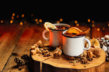 Hot mulled wine in white rustic mugs with spices and citrus fruit on wooden surface. Space for...