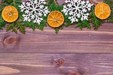 Obraz na płótnie Canvas Christmas decoration with thuja branches, snowflakes and tangerines on wooden background. Top view