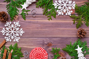 Christmas decoration with thuja branches, snowflakes, pine cones, cinnamon and candy on wooden background. Top view