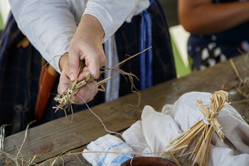 Woman shows how to make a straw human as the toy for children. Traditional Russian folk art