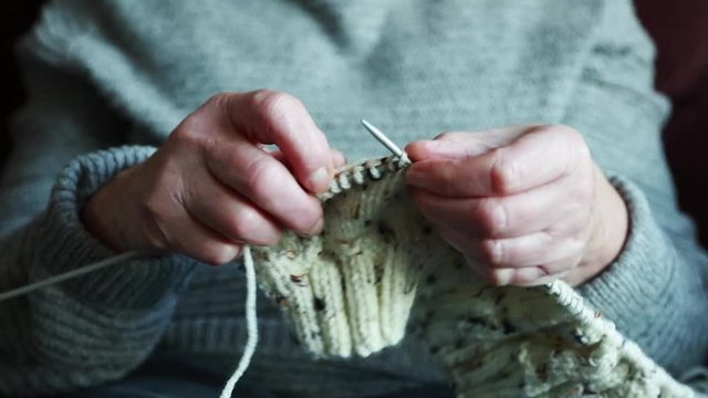 Close up of an elderly ladies hands knitting a woollen jumper