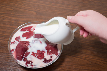 female hand pours raw chicken liver with milk so that it does not taste bitter