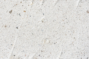 Rough surface of concrete close-up interspersed with grains of sand and pebbles