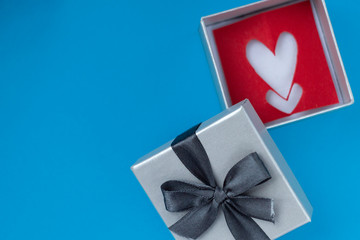 background for Valentine's day holiday, gift for Valentine's day, heart and gift box on blue background