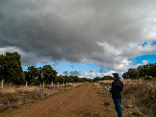 A drone pilot piloting with the remote control with smartphone in his hands in a dirt road in the forest