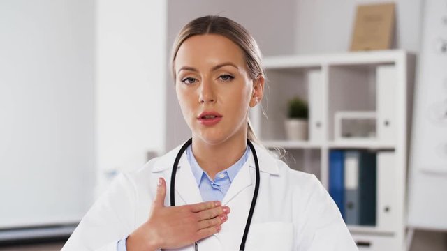 medicine, healthcare and technology concept - female doctor participating in video call or consultation pointing at cheast at hospital