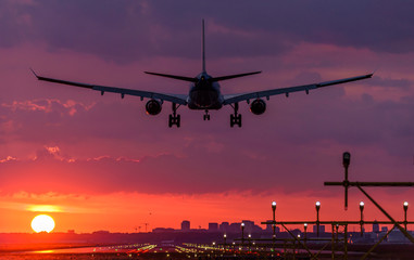 Passenger plane is landing during a wonderful sunrise.