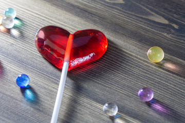 Red lollipop heart for Valentine's Day on wooden background
