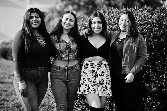 Group of four happy and pretty latino girls from Ecuador posed at street.