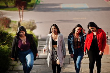 Group of four happy and pretty latino girls from Ecuador posed at street.