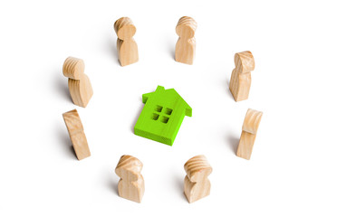 Wooden figurines of people stand around a green house. Search for a new home and real estate. Buying or selling a home. Moving to a new home. Rent or construction. Buying a property. Investments