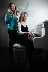 Young beautiful girls playing the piano. Girls learn to play a musical instrument.