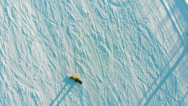 Aerial video of skiers and snowboarders going down the slope in winter day. Winter Sports. Skiers and snowboarders on ski resort in winter season. 4K video, aerial footage.