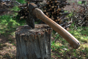 Old ax in hemp, on the background of firewood.